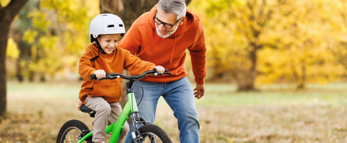 A man teaching his grandson to ride a bike.